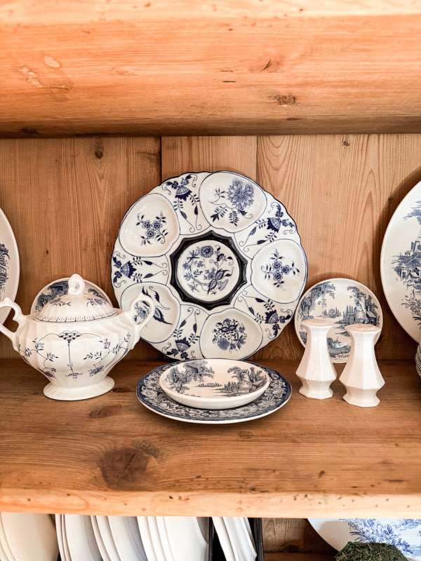 Blue and white dishes in kitchen cupboard shelves with decor