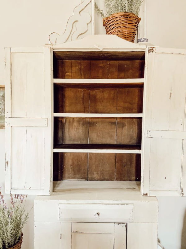 Empty white antique cabinet in bedroom of farmhouse.