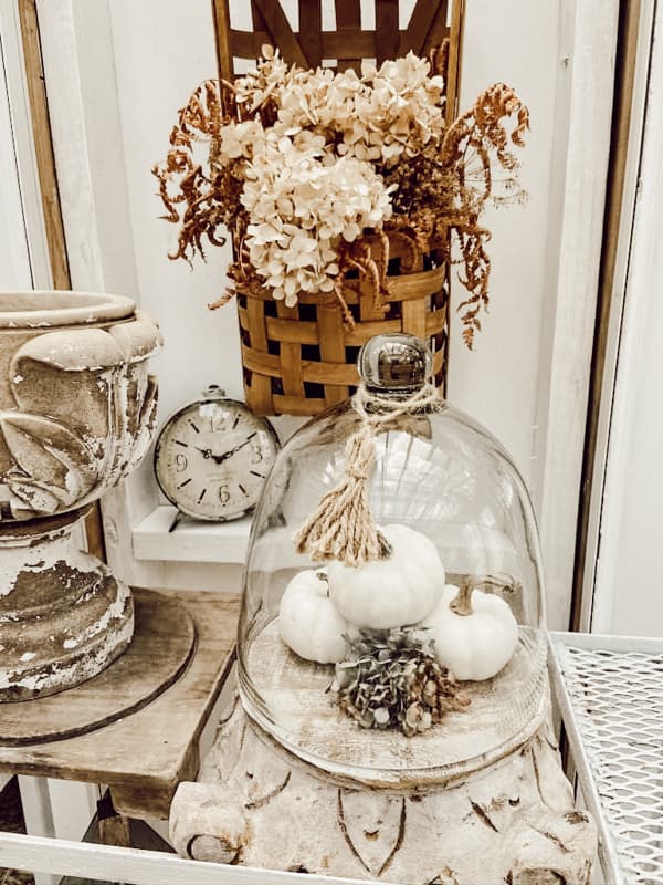 DIY Pumpkin craft displayed under glass .
Vintage basket with flowers hanhing on wall.