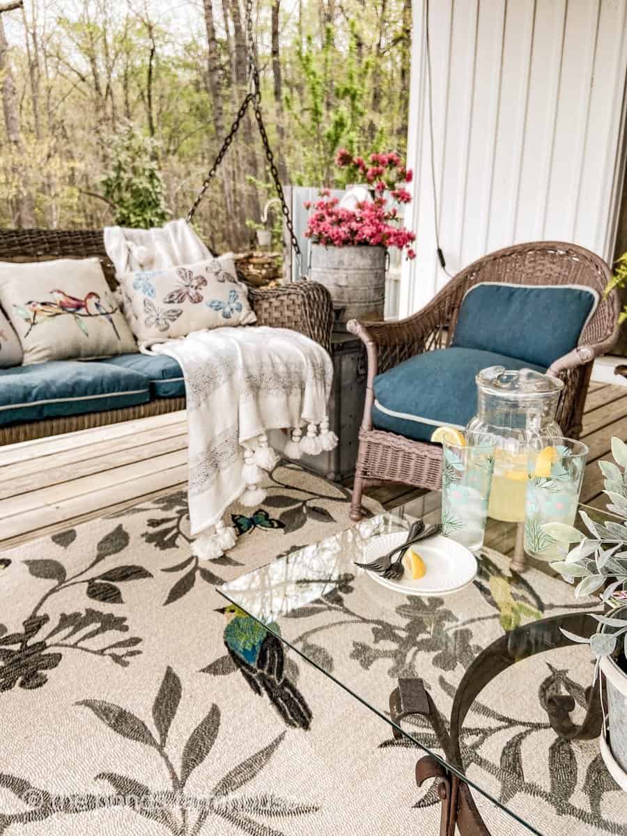 Cozy Seating area with porch swing, custions, and pillows.  Coffee table with cold lemonade and vintage glasses.