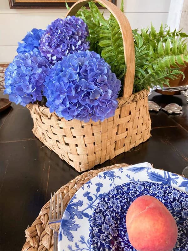 Blue hydrangeas in basket with blue and white dishes