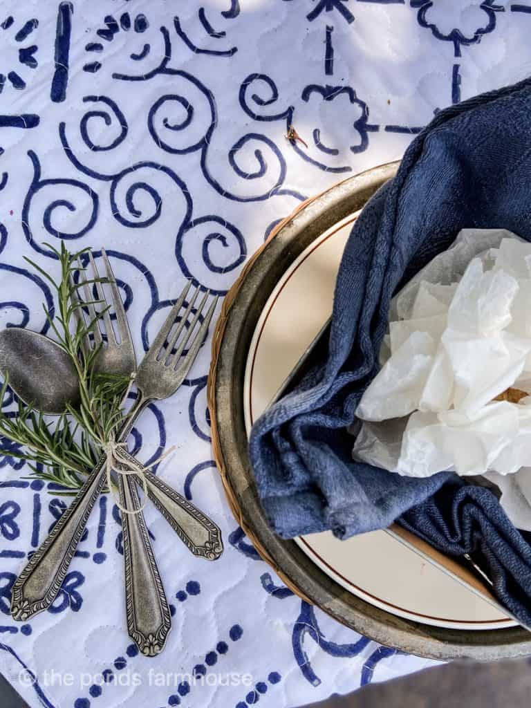 Silverware tied with twine and rosemary sprigs for easy picnic table setting.