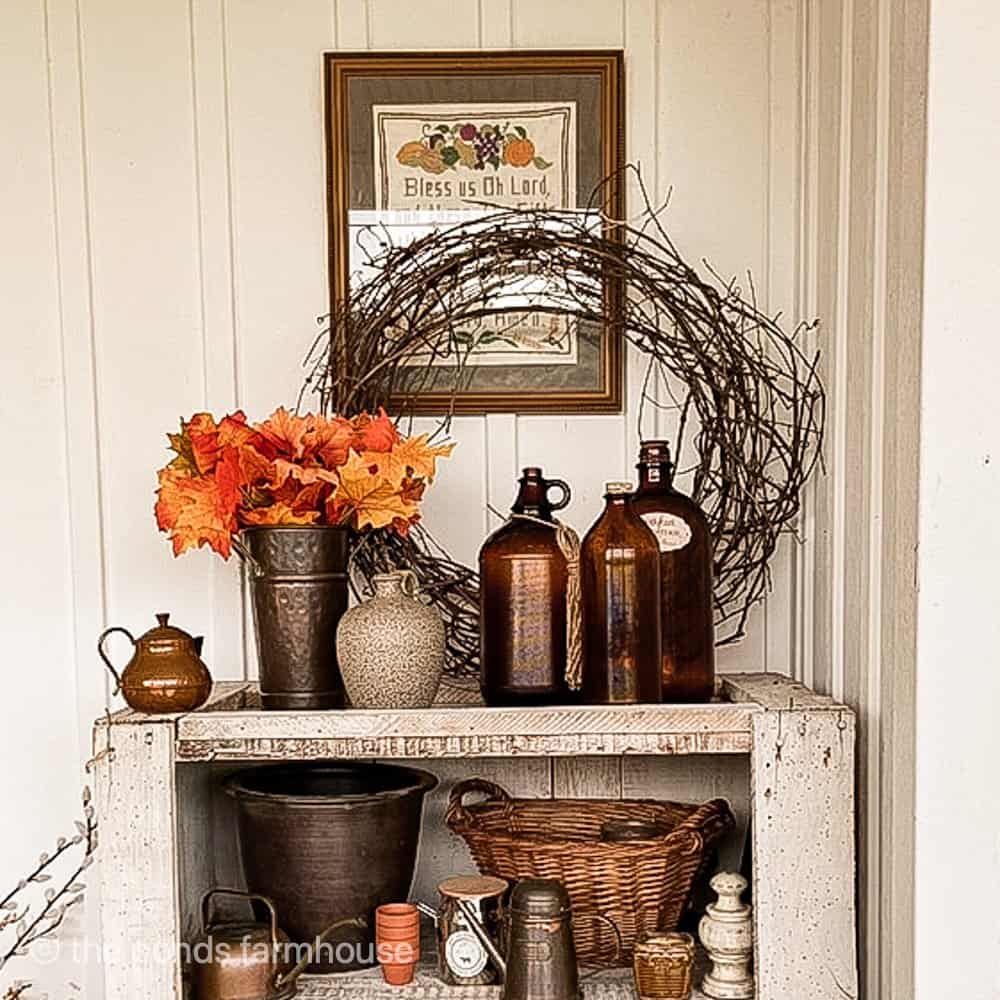 Thrifted vintage jugs with grapevine wreath on farmhouse porch.