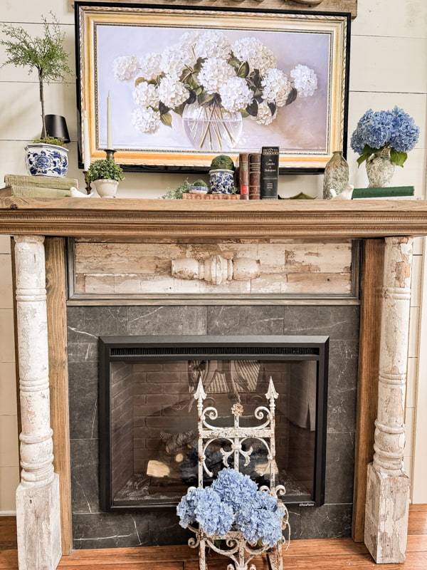 Blue hydrangeas on DIY mantel with blue and white accessories.  