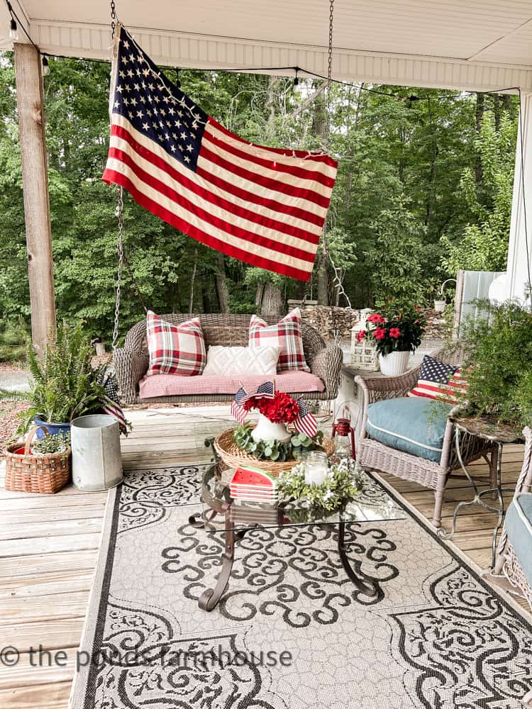 Memorial Day decorations, American flag, pillows, watermelon plates. Iron coffe table, porch swing.