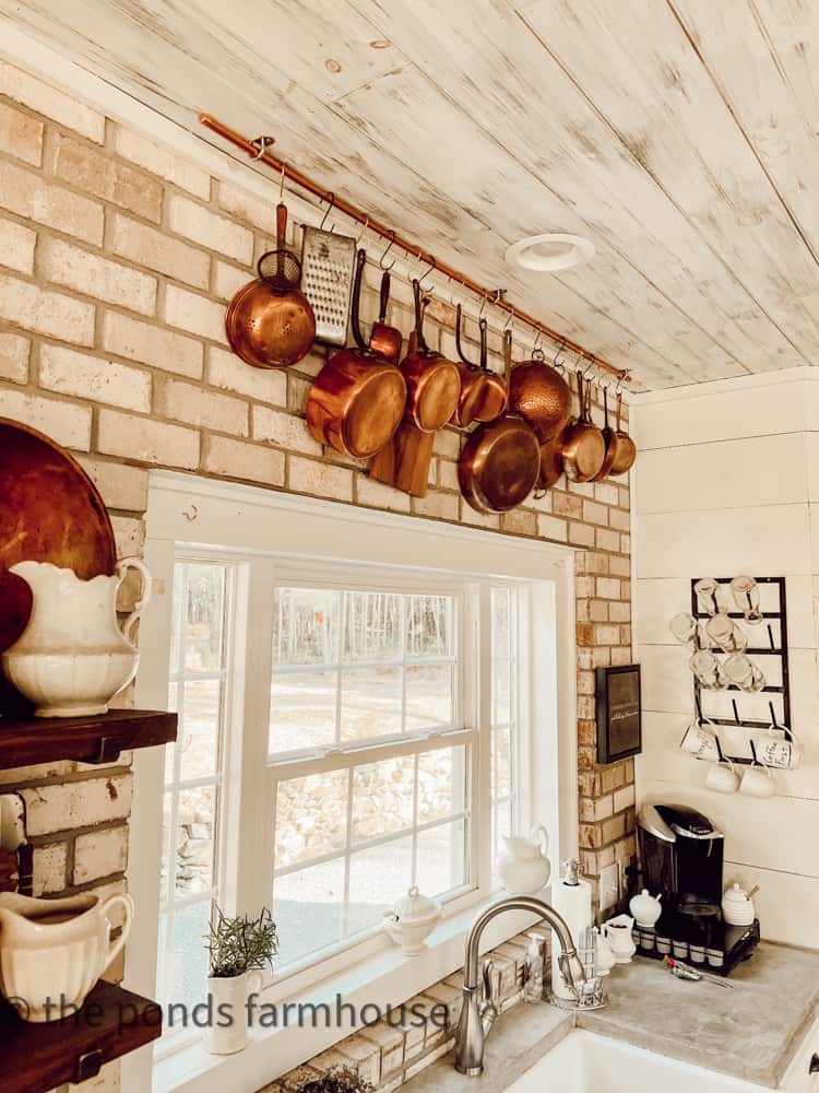 https://www.thepondsfarmhouse.com/wp-content/uploads/2022/10/DIY-Copper-Pot-Hanging-Rack-copper-pots-on-brick-wall-in-kitchen-1.jpg