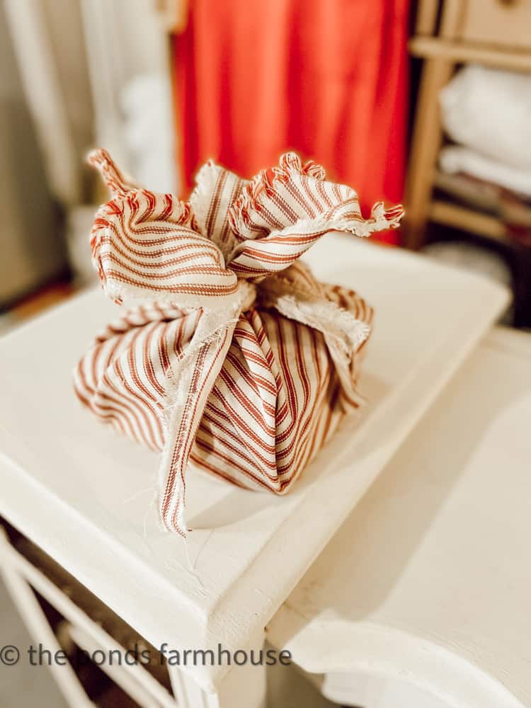 Stylish christmas gift wrapped in fabric on rustic table with