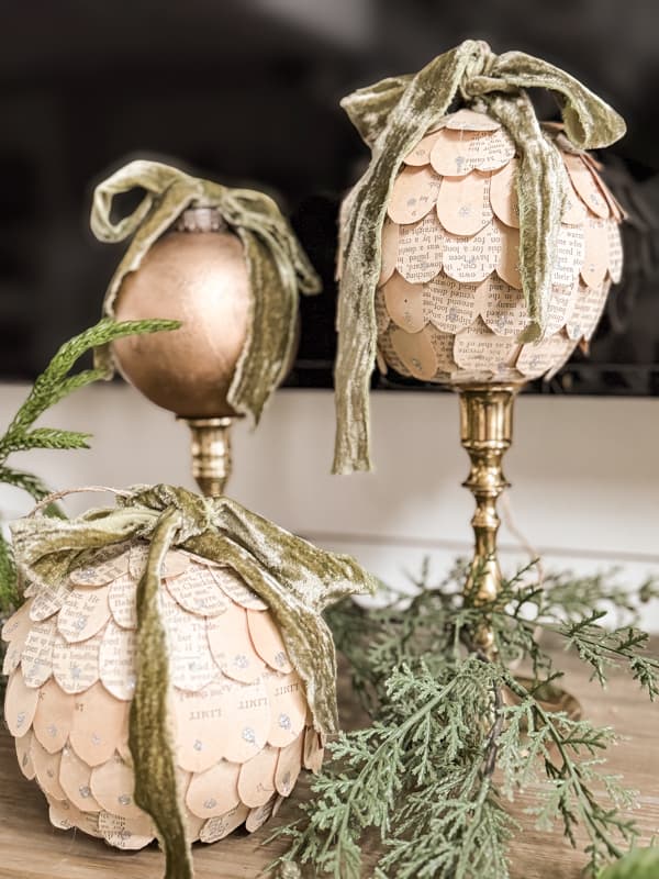 Upcycled Old Book Page Dollar Tree Ornaments with green ribbon on vintage brass candlesticks.