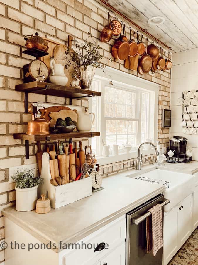 https://www.thepondsfarmhouse.com/wp-content/uploads/2023/03/open-shelves-with-cutting-boards-and-rolling-pins-with-copper-pot-hanging-rack-in-background.-.jpg