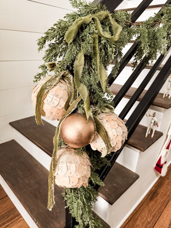 Banister with old book page Christmas ornaments and green ribbon