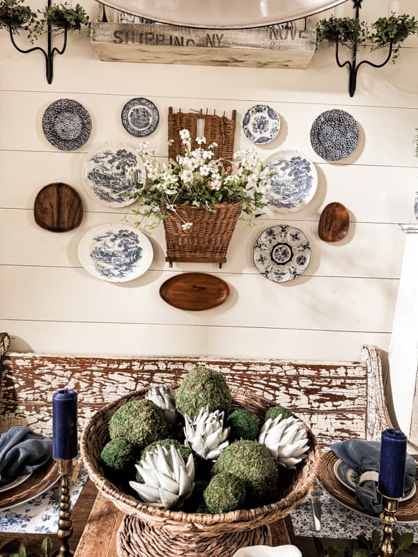 basket centerpiece with moss and artichoke decor for decorating with plates on wall of farmhouse dining room.