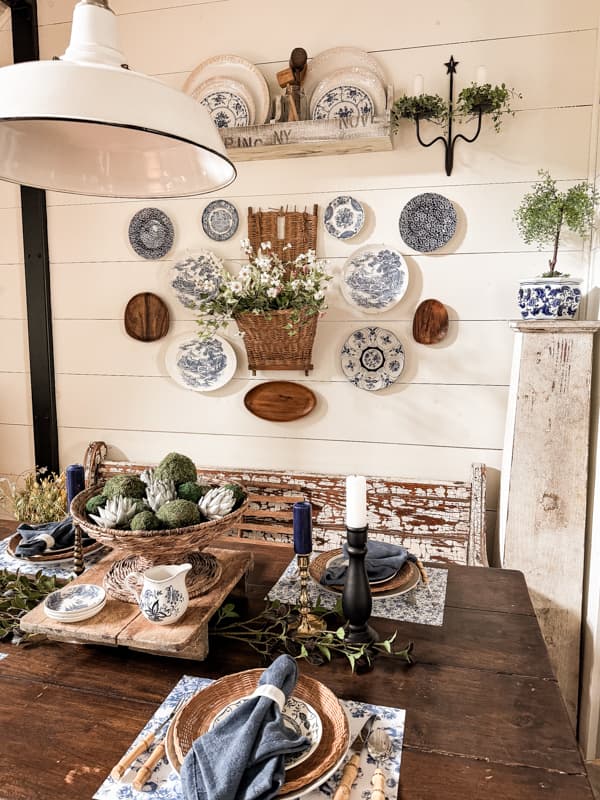 Decorate dining room wall with plate wall decor and vintage basket beside the farmhouse table. 