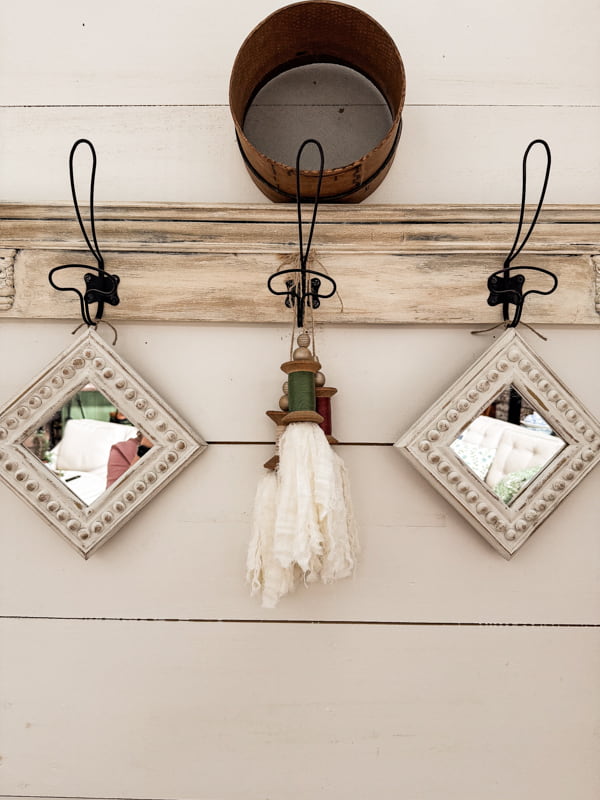 Hang thrift store mirrors from a wall rack with DIY spool tassels.  