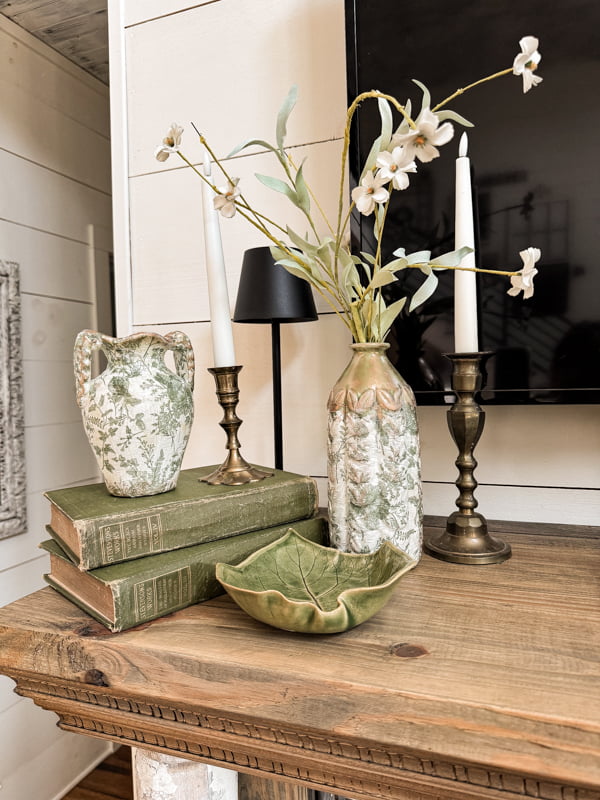 Magnolia Vase knock-off vignette on mantel with vintage candlestick, thrifted leaf bowl and old green books
