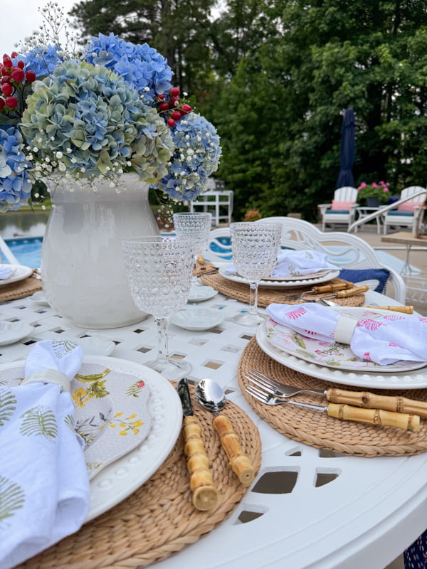Poolside table ideas with thrifted placemats and bamboo silverware, hydrangea centerpiece and beaded wine glasses