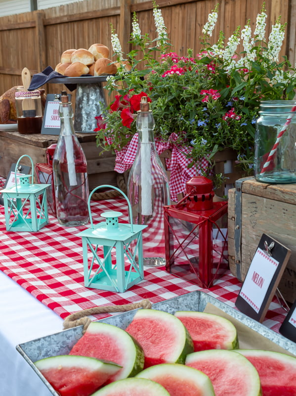 Red and white picnic table with lanterns and watermelon
