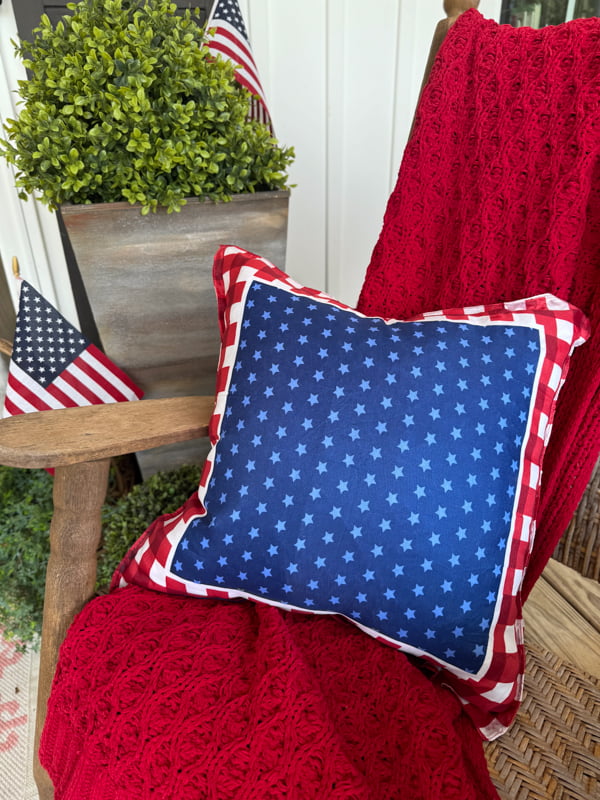 Red, white and blue Dollar Tree Patriotic Pillow Cover on porch rocker with red throw blanket. 