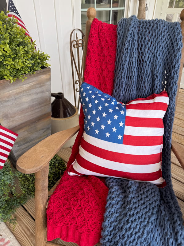Flag pillow cover with Dollar Tree finds on front porch rocking  chair with red and blue throw blankets.