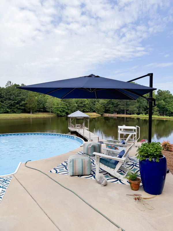 View of pool and pier at the Ponds with umbrella and seating area. 
