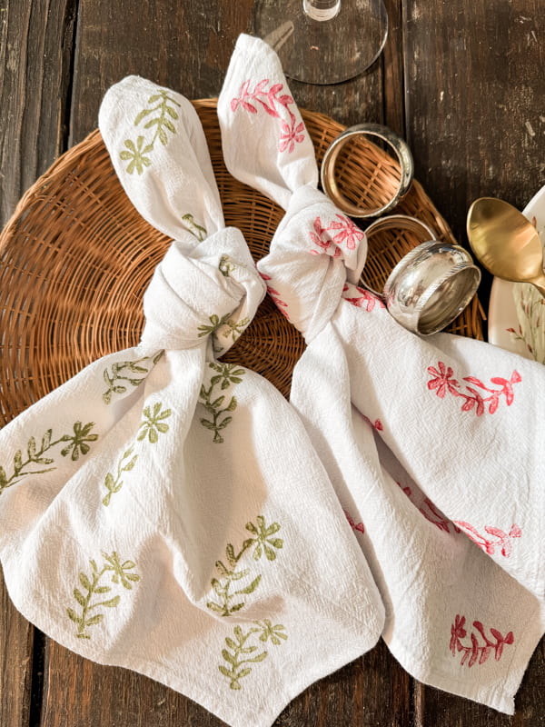 DIY Custom Block Print Napkins tied into a knot on woven tray with silver napkin rings.