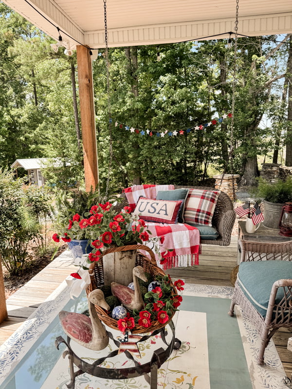 Patriotic red, white and blue summer porch decorations.  with USA pillow and rustic coffee table vignette.