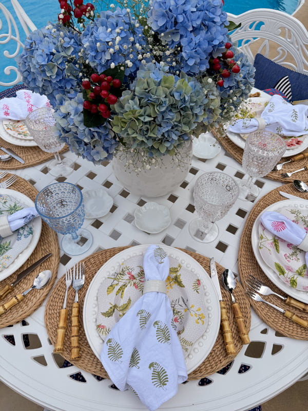 Blue hydrangea centerpiece in ironstone vase with baby's breath and red berries.  Thrifted plates and DIY napkins