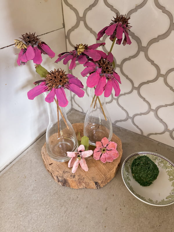Add purple coneflowers made of gumballs and pinecone scales to bud vases to decorate countertops.  