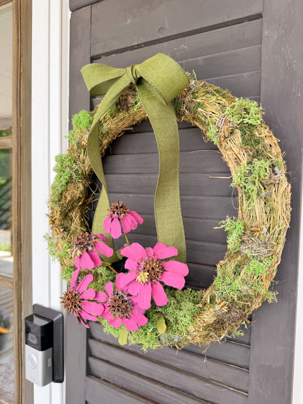 Purple cornflower summer wreath made with foraged pinecone scales and gumballs on front porch. Summertime wreath ideas.