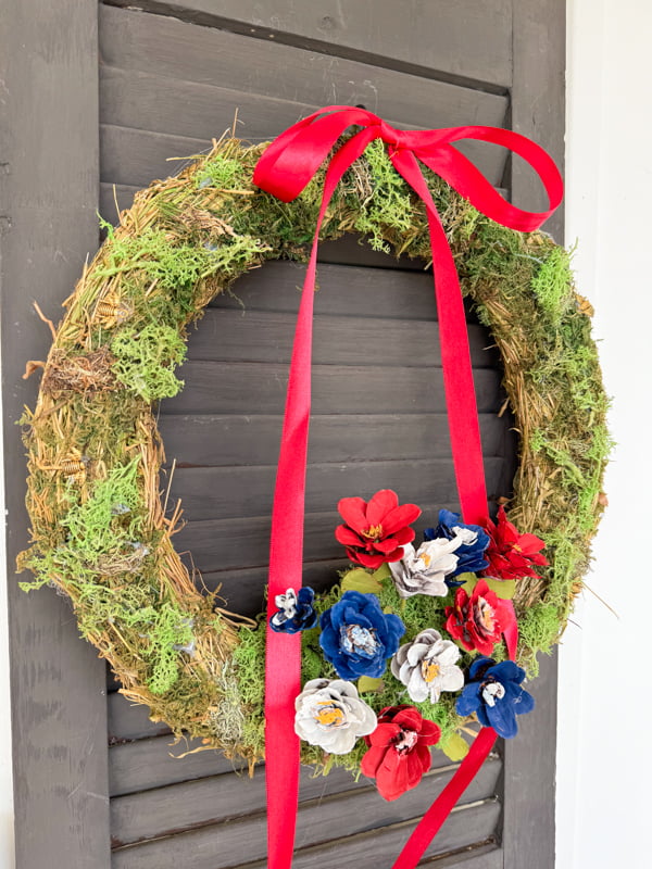 Patriotic  summertime Wreath ideas with a moss frame with red, white and blue painted pinecone flowers and red ribbon. 