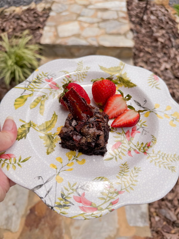 salted caramel dark chocolate brownies recipe with candied bacon and strawberries on floral plate