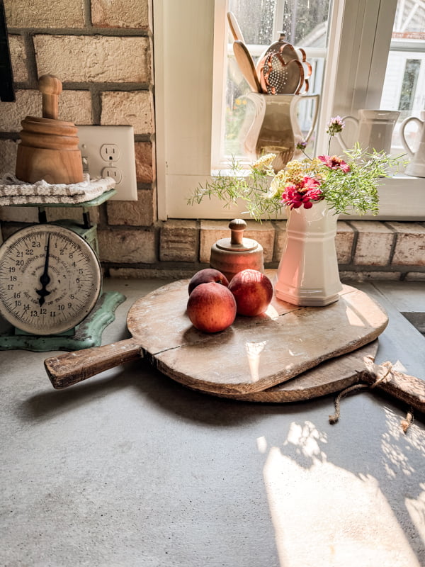 Two vintage breadboard staked with peaches and ironstone pitcher filled with fresh zinnas, and daisies.  