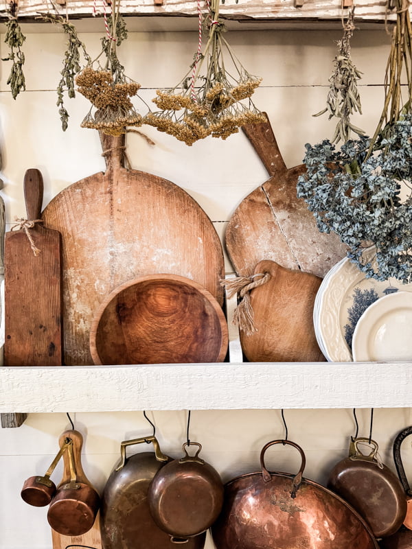 DIY Wall Plate Rack filled with woods and whites for farmhouse decorations with copper pots and vintage breadboards.  