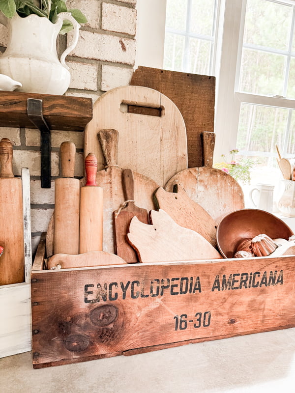 Wood Boards fill a encyclopedia Crate on kitchen countertops.