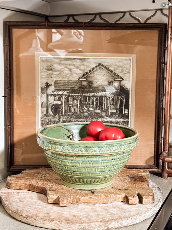 Thrifted art with vintage bowl of red tomatoes on kitchen countertop.