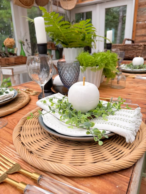 Thirft Store Woven plate charger for a rustic table decoration. with fringed napkin and DIY artificial apple in white and gold.