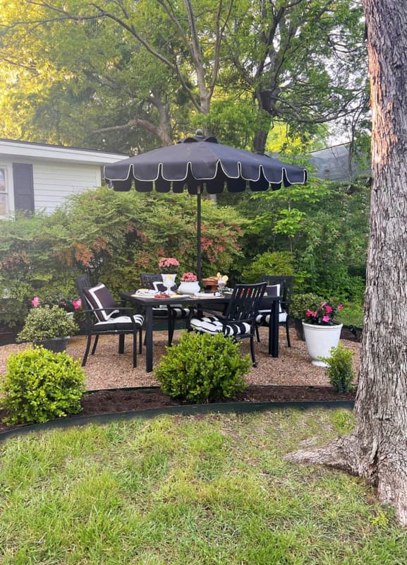 Budget outdoor living space created with pea gravel for cozy outdoor dining. 