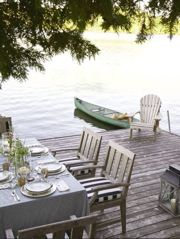 Lakeside dining area with teak chairs and old canoe with Adirondack chair.