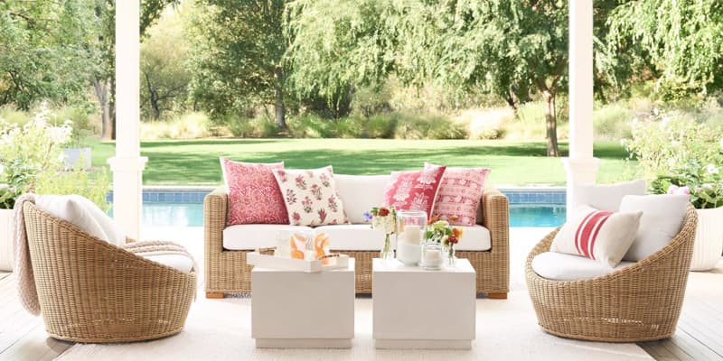 Poolside seating area from Pottery Barn with rattan seating, white cushions and pink pillows