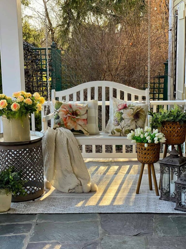 Outdoor Furniture for Small Spaces includes a white porch swing, side table and wicker planters