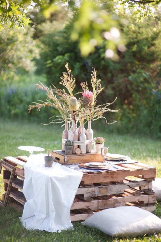 Creative Outdoor Living Space Ideas on budget using pallet wood to make a table for a picnic with pillows for seats.