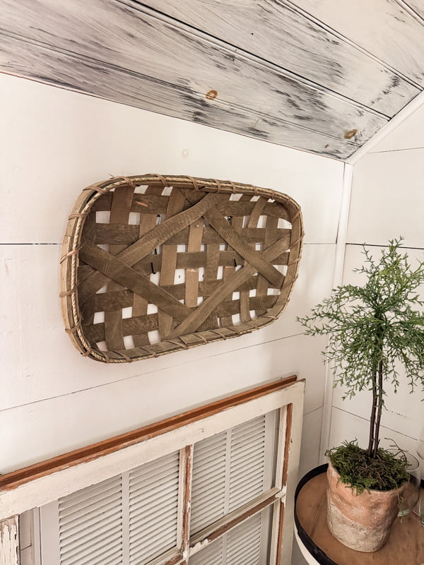 Faux tobacco barn wall basket under staircase with old window covering heat exchange vent.  