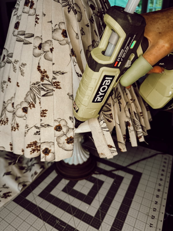 Use hot glue to attach the pleats at the bottom of the upcycled fabric lampshade