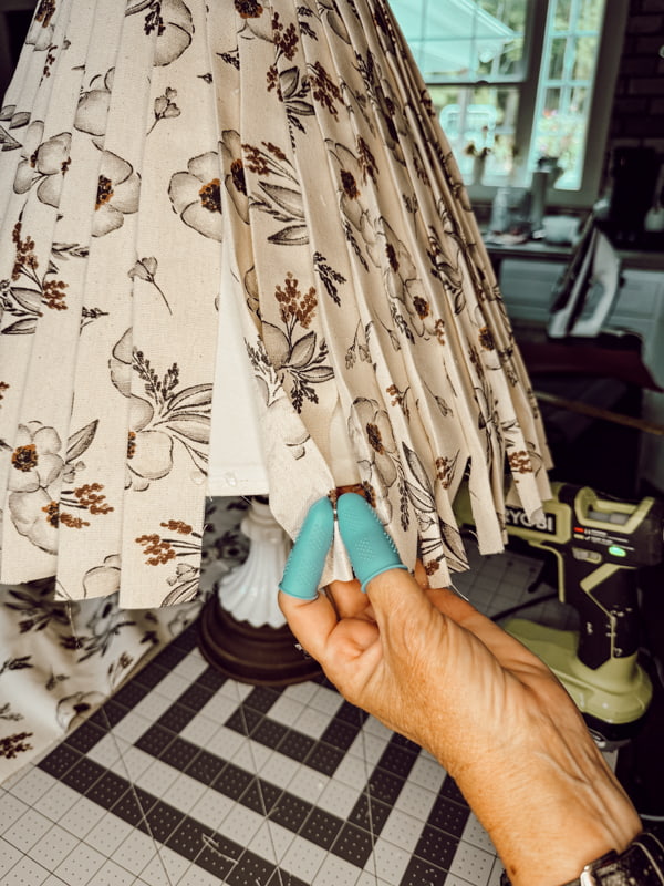 Use hot glue to attach the pleats at the bottom of the upcycled fabric lampshade