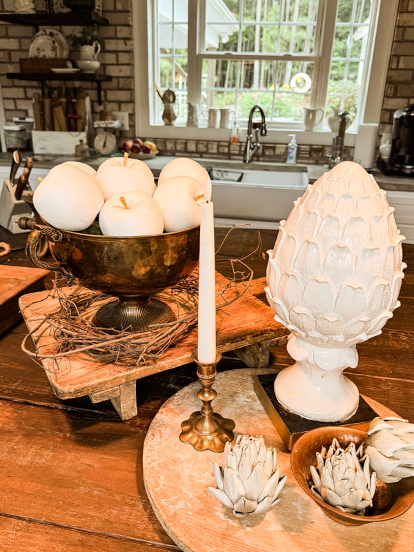 Upcycled Apples in a Vintage Brass Bowl with a large artichoke and small artichokes on breadboards. 