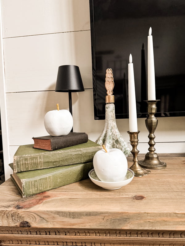 two apples on mantel with old books and napkin decoupage bottle with vintage brass candlesticks 