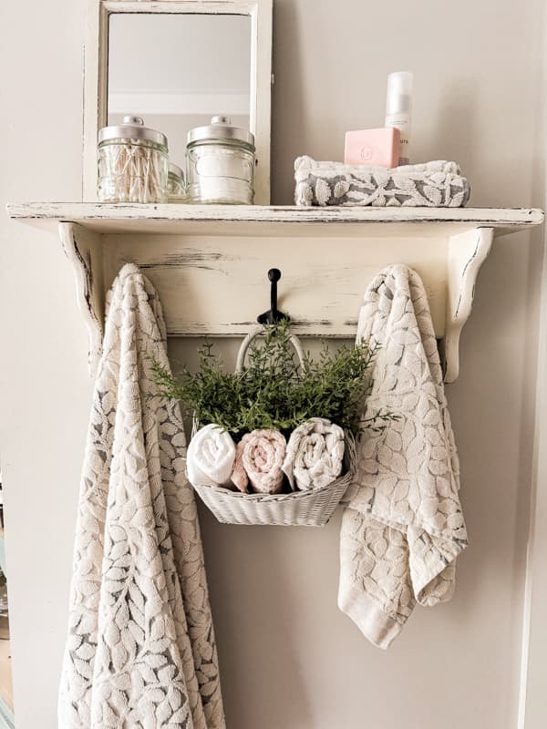 Hanging Basket ideas with thrifted basket filled with greenery and hand towels for bathroom.