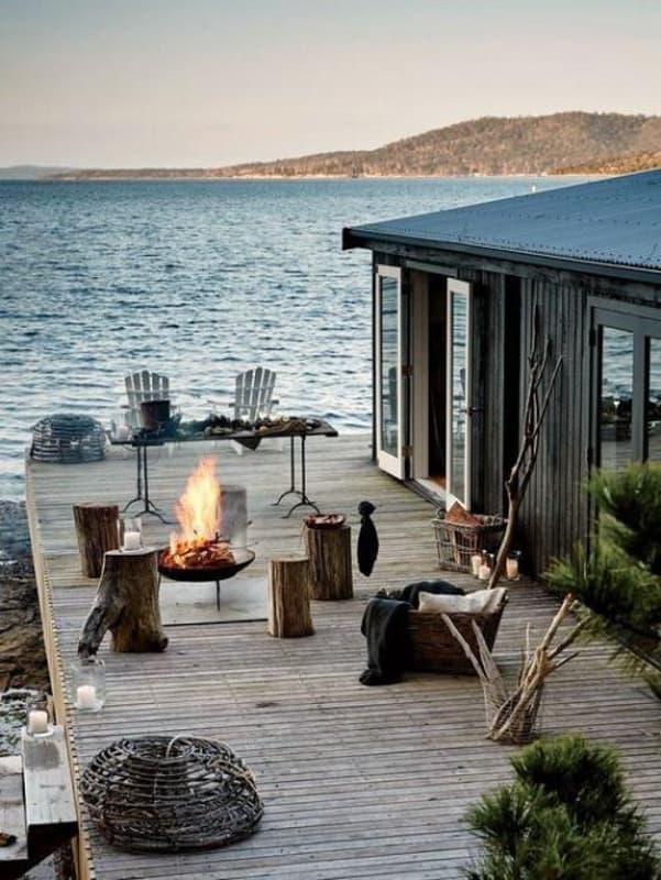 Rustic lakeside retreat with firepit and logs for seating.  