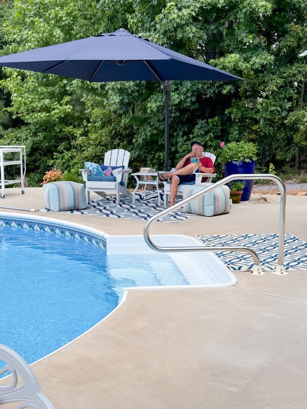 Creative outdoor living space around the pool with cozy reclining adirondack chairs and puff ottomans.  