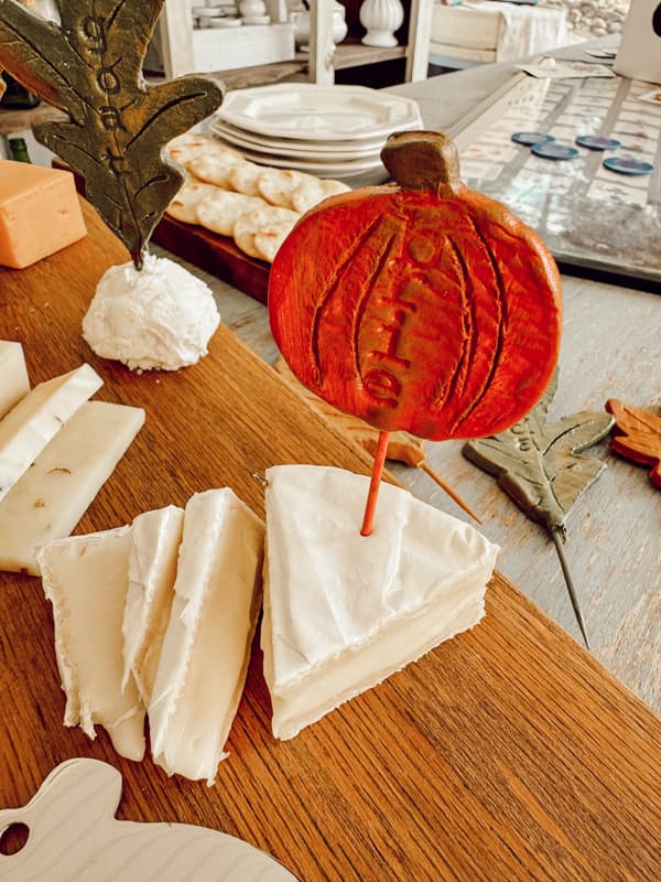 Air-Dry Clay DIY Brie Cheese Marker in a pumpkin shape on a cheese board.