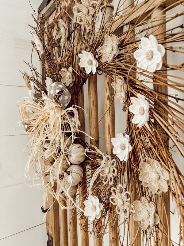 DIY autumn wreath with pumpkins and burlap flowers on barn door